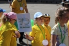 Dzieci trzymające transparenty z logiem jubileuszu miasta.