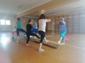 grupa osób ćwicząca na sali gimnastycznej przy ławce 