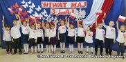 Dzieci ubrane na galowo trzymają biało-czerwone flagi