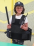 Dziewczynka pozuje w kamizelce kuloodpornej, czapce, z pałką policyjną i krótkofalówką