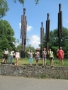 Grupa dzieci pozuje na tle wysokich, drewnianych rzeźb