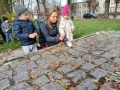 Dzieci z opiekunką stawiają znicze na pomniku