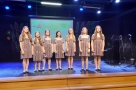 Siedem dziewcząt w złotych sukienkach na scenie