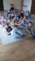 Dzieci siedzą na szarym dywanie.