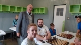 przy szachownicach siedzą chłopcy i dwaj mężczyżni