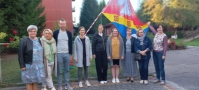 Zdjęcie przedstawia delegację nauczycieli z Niemiec na tle flagi z Hattstedt.