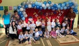 dzieci wraz z nauczycielami pozują do wspólnej fotografii na tle ściany udekorowanej w niebieskie balony