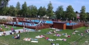 ludzie leżący na trawie oraz pływający w basenie