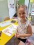 Dziewczynka prezentuje swoją pracę narysowaną pastelami.