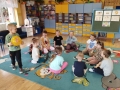  dzieci malują, bawią się, siedzą na dywanie i odnawiają temat z nauczycielem prowadzącym