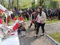 Zuchy wraz z paniami składają biało – czerwone goździki pod obeliskiem im. Konstytucji 3 Maja w miejskim parku. 