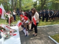 Zuchy wraz z paniami składają biało – czerwone goździki pod obeliskiem im. Konstytucji 3 Maja w miejskim parku. 