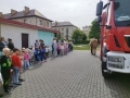 dzieci uczestniczące w ćwiczeniach ewakuacyjnych.W tle znajduje się czerwony wóz strażacki