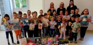 grupa dzieci z panią dyrektor i nauczycielkami. Dzieci trzmyjaą zabawki i gry