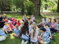 dzieci siedzą na trawie i słuchają opowieści