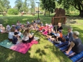 dzieci siedzą na trawie i słuchają opowieści
