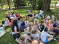dzieci siedzą na trawie i słuchają opowieści