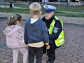 policjant w mundurze kuca przy dwójce dzieci