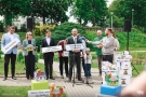 kilka osób na konferencji prezentują planze z hasłami projetu, mężczyzna przemawia do mikrofonu