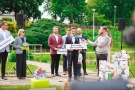 kilka osób na konferencji prezentują plansze z hasłami projetu, mężczyzna przemawia do mikrofonu