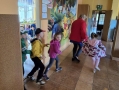 dzieci i opiekunka biegną po korytarzu przedszkolnym