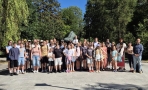 duża grupa osób pozuje do zdjęcia przy pomniku żubra
