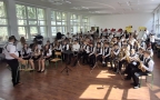 członkowie orkiestry grają na instrumentach. Przed orkiestrą stoi dyrygent