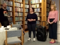 dwie kobiety i mężczyzna stoją przed rekgałami z książkami