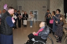 Duchowny Nikita Kazakiewicz składa jubilatce życzenia i wręcza kwiaty