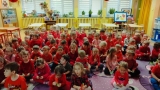  Dzieci siedzą na dywanie, w rękach trzymają karteczki w dwóch kolorach.