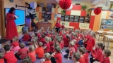  Dzieci siedzą na dywanie, w rękach trzymają karteczki w dwóch kolorach.